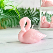Load image into Gallery viewer, Pink flamingo candle on a white surface with greenery in the background