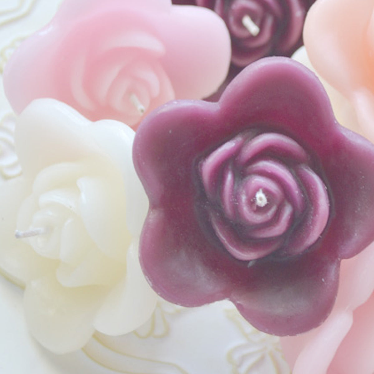A colorful array of rose candles in plum, ivory and pinks grouped together. 