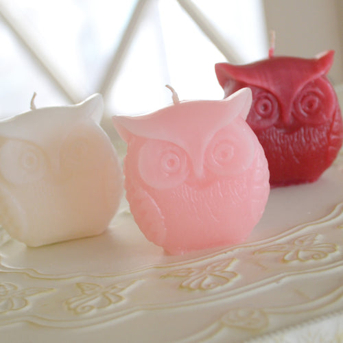 three owl candles in the colors, red, pink and white